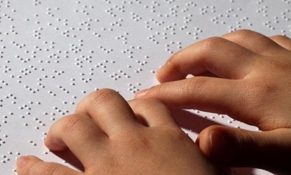 jari meraba di atas kertas dengan huruf Braille