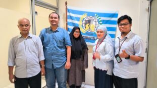 Lima orang berdiri berjajar di dalam ruangan di depan bendera PERTUNI bergaris biru-putih, semuanya tersenyum ke arah kamera. Dari kiri ke kanan: seorang pria berkemeja abu-abu lengan panjang, pria berkemeja jeans biru dan celana jins, perempuan berhijab hitam dengan gamis cokelat, perempuan berhijab abu-abu muda dengan atasan abu-abu muda dan rok gelap, serta pria berkacamata dengan kemeja abu-abu muda dan kartu identitas yang tergantung di leher.